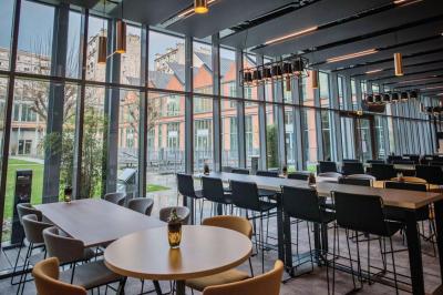 Un technicien supervise un enregistrement en studio, avec trois personnes chantant derrière une vitre insonorisée.