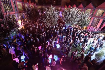 Un technicien supervise un enregistrement en studio, avec trois personnes chantant derrière une vitre insonorisée.