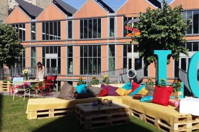 Un technicien supervise un enregistrement en studio, avec trois personnes chantant derrière une vitre insonorisée.