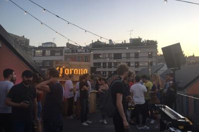 Un technicien supervise un enregistrement en studio, avec trois personnes chantant derrière une vitre insonorisée.