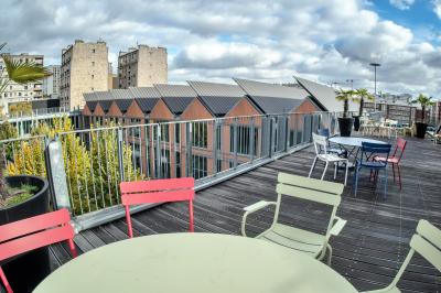Un technicien supervise un enregistrement en studio, avec trois personnes chantant derrière une vitre insonorisée.