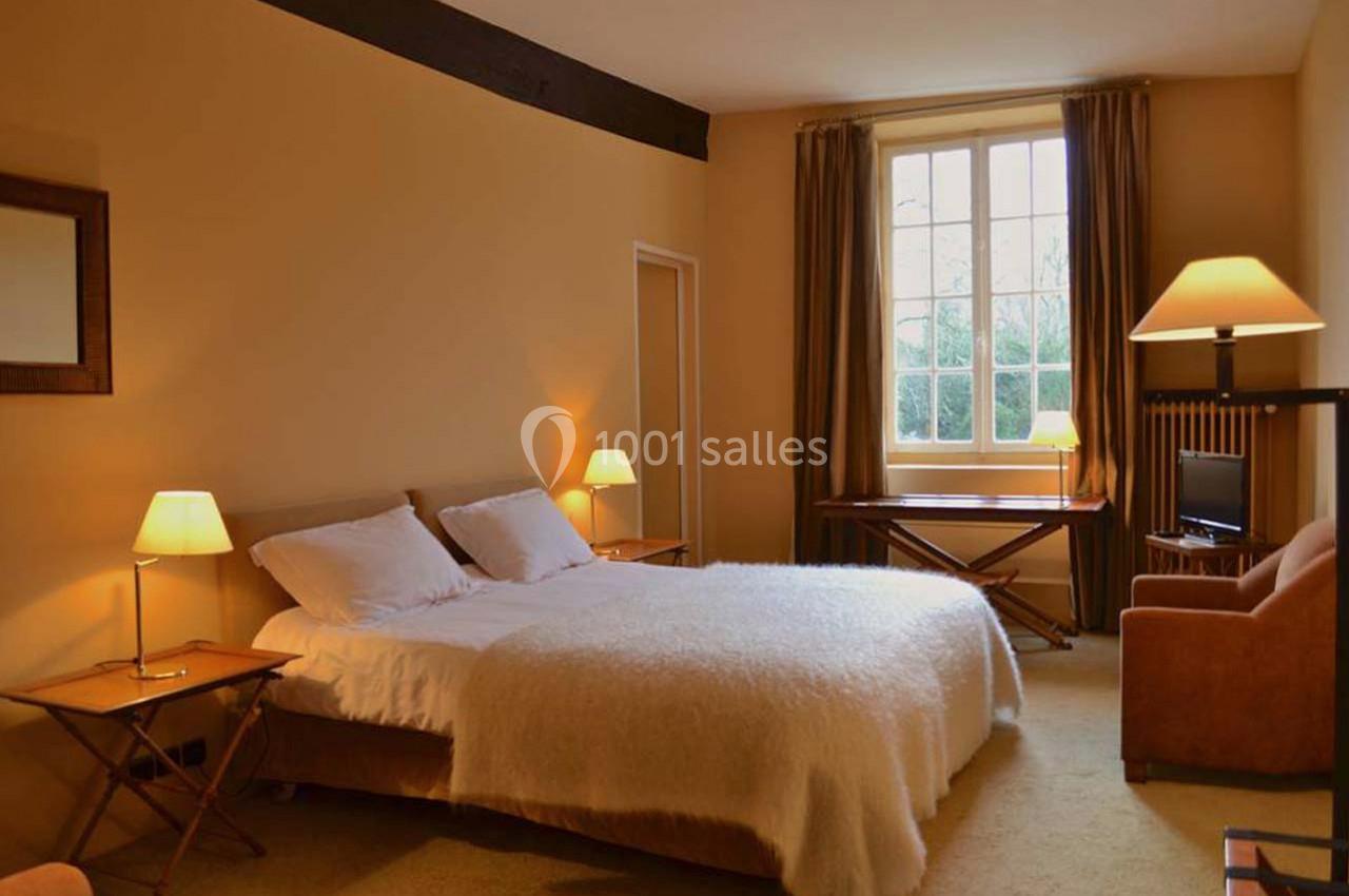 Chambre lumineuse avec un grand lit, des lampes de chevet, un bureau, une télévision et une grande fenêtre donnant sur l…