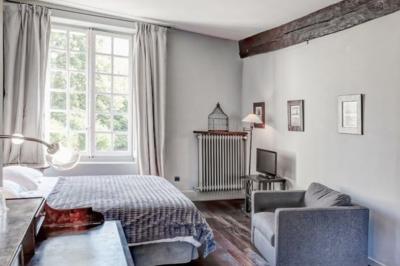 Chambre lumineuse avec un grand lit, des lampes de chevet, un bureau, une télévision et une grande fenêtre donnant sur l…