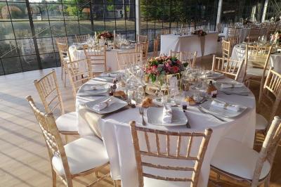 Chambre lumineuse avec lit double, fauteuil gris, bureau en bois, fenêtre à carreaux et poutres apparentes.