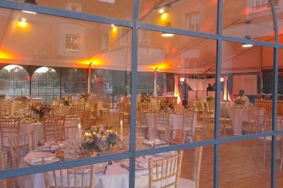 Chambre lumineuse avec lit double, fauteuil gris, bureau en bois, fenêtre à carreaux et poutres apparentes.