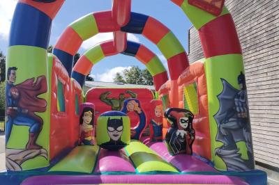 Structure gonflable jungle avec animaux et toboggan, entourée de feuilles, avec détails de location et caractéristiques.