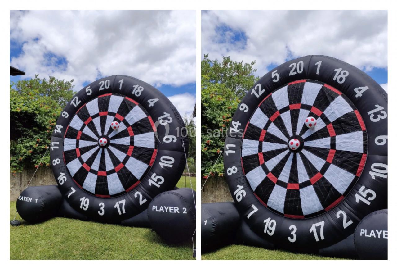 Cible géante de fléchettes gonflable en extérieur, avec deux balles accrochées au centre.