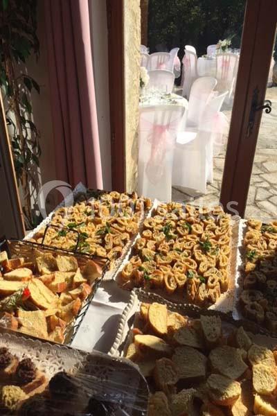 Plateaux de toasts et roulés apéritifs disposés sur une table près d'une porte ouverte donnant sur une terrasse.