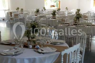 Matériel de sonorisation et d'éclairage installé sur deux tables recouvertes de nappes blanches dans une pièce lumineuse.