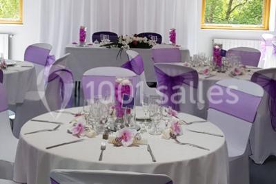 Matériel de sonorisation et d'éclairage installé sur deux tables recouvertes de nappes blanches dans une pièce lumineuse.