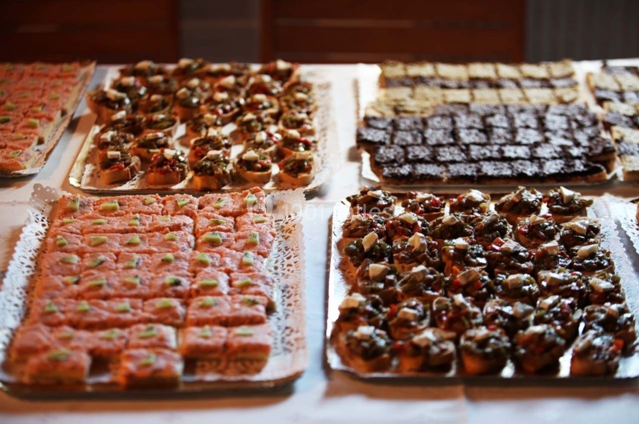 Plateaux de canapés variés disposés sur une table, incluant des options au saumon, légumes et chocolat.