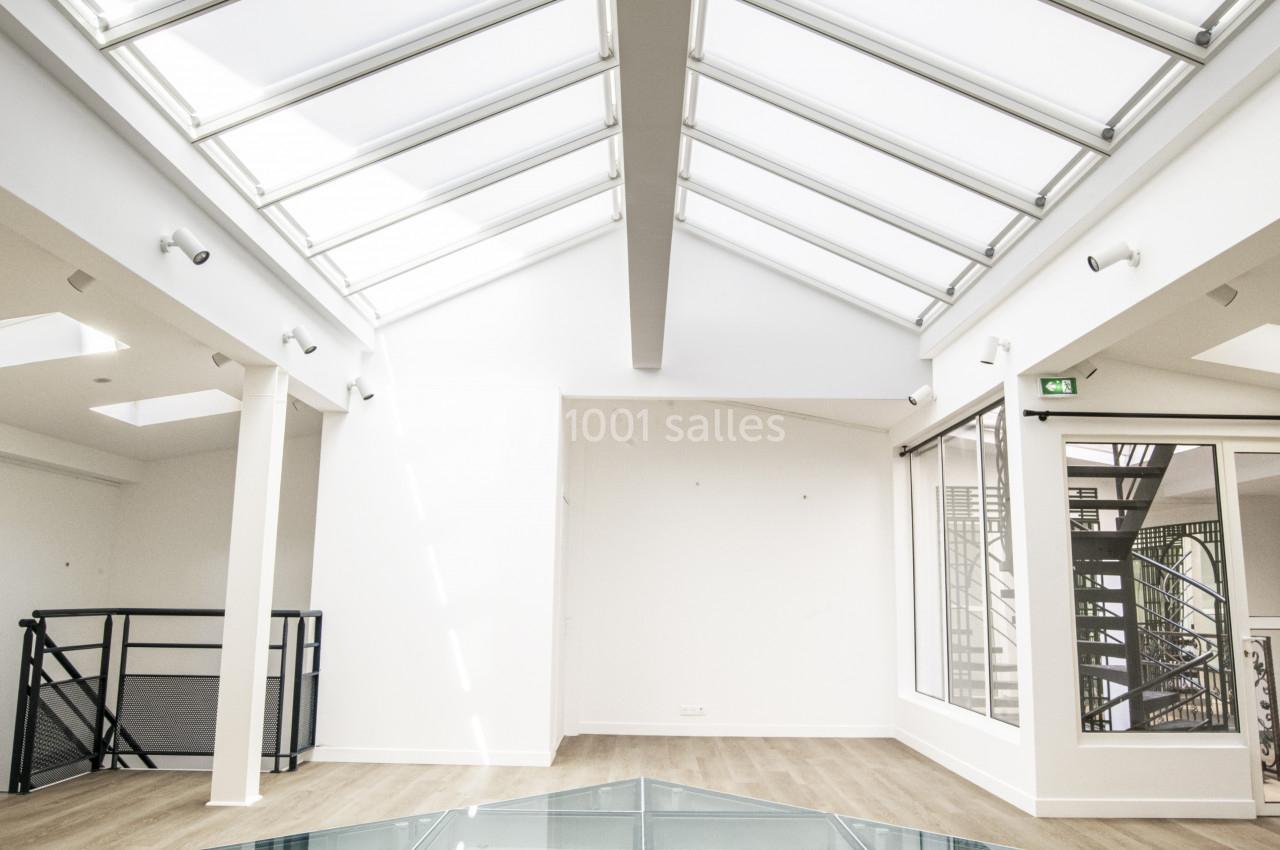 Plafond vitré laissant entrer la lumière naturelle dans une pièce lumineuse avec un sol en verre et parquet clair.