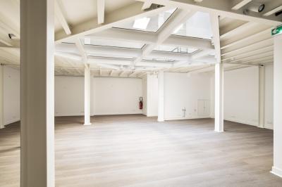 Espace intérieur lumineux avec parquet clair, verrière au plafond et ouverture vitrée au sol.
