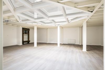 Espace intérieur lumineux avec parquet clair, verrière au plafond et ouverture vitrée au sol.