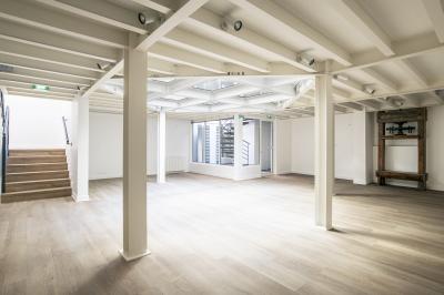 Espace intérieur lumineux avec parquet clair, verrière au plafond et ouverture vitrée au sol.