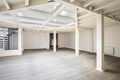Espace intérieur lumineux avec parquet clair, verrière au plafond et ouverture vitrée au sol.