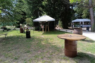 Salon lumineux avec mobilier en résine tressée, plantes vertes, tapis rond en jute et rideaux sombres.