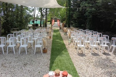 Salon lumineux avec mobilier en résine tressée, plantes vertes, tapis rond en jute et rideaux sombres.