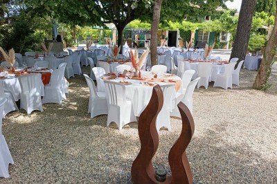 Salon lumineux avec mobilier en résine tressée, plantes vertes, tapis rond en jute et rideaux sombres.