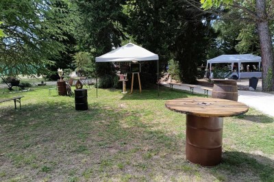Salon lumineux avec mobilier en résine tressée, plantes vertes, tapis rond en jute et rideaux sombres.