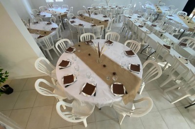 Salon lumineux avec mobilier en résine tressée, plantes vertes, tapis rond en jute et rideaux sombres.