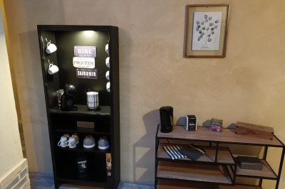 Salon lumineux avec mobilier en résine tressée, plantes vertes, tapis rond en jute et rideaux sombres.