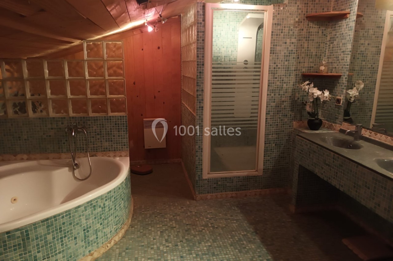 Salle de bain mansardée avec baignoire d'angle, douche, double vasque et carrelage en mosaïque verte.