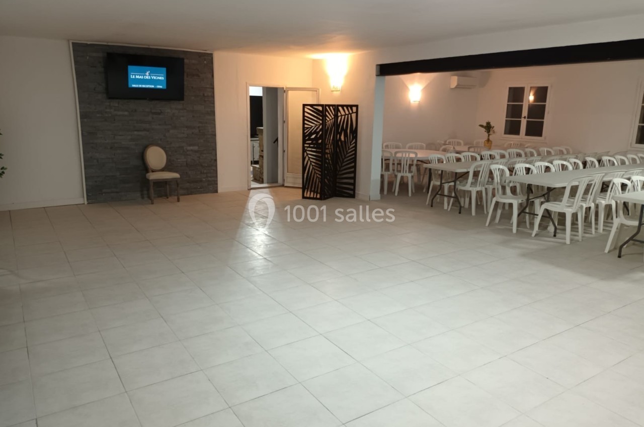 Salle spacieuse avec carrelage clair, chaises blanches alignées, écran mural et cloison décorative noire.