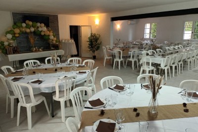 Salon lumineux avec mobilier en résine tressée, plantes vertes, tapis rond en jute et rideaux sombres.
