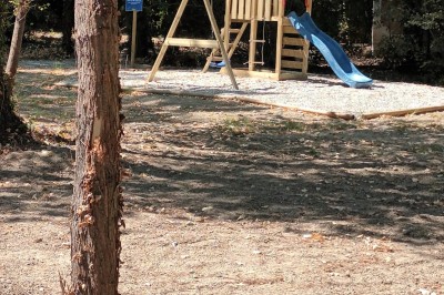 Salon lumineux avec mobilier en résine tressée, plantes vertes, tapis rond en jute et rideaux sombres.