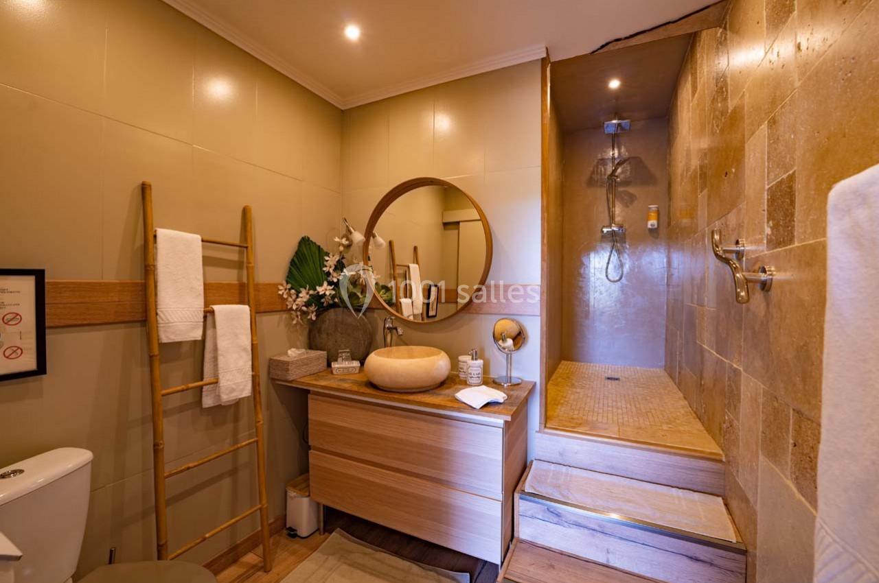 Salle de bain moderne avec douche à l'italienne, meuble en bois, miroir rond et échelle porte-serviettes.