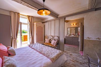 Vue d'une piscine entourée de végétation, avec un jacuzzi, des parasols et un paysage de campagne en arrière-plan.