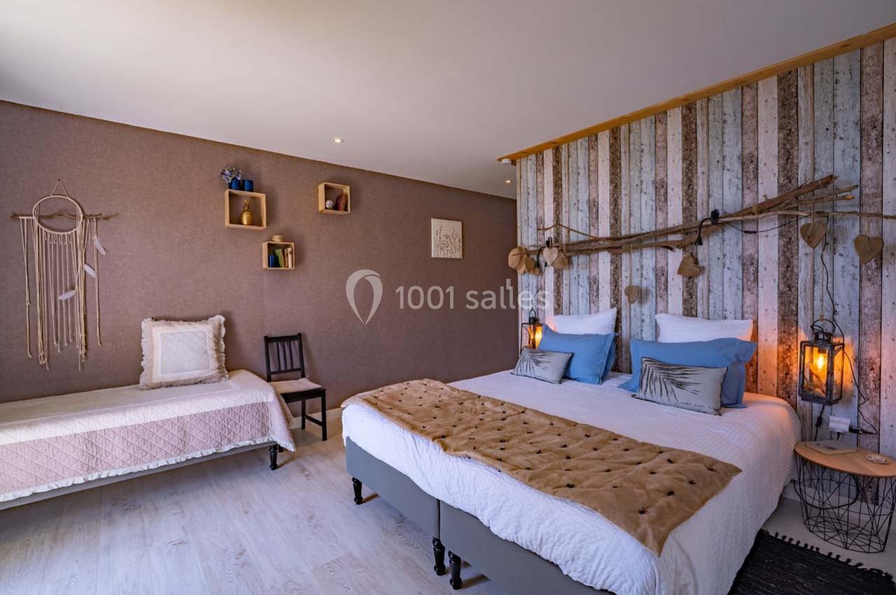 Chambre avec lit double, lit simple, décoration murale en bois et éclairage chaleureux.