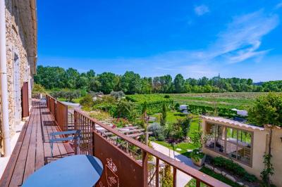 Vue d'une piscine entourée de végétation, avec un jacuzzi, des parasols et un paysage de campagne en arrière-plan.