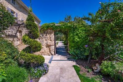 Vue d'une piscine entourée de végétation, avec un jacuzzi, des parasols et un paysage de campagne en arrière-plan.
