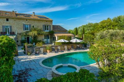 Vue d'une piscine entourée de végétation, avec un jacuzzi, des parasols et un paysage de campagne en arrière-plan.