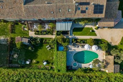 Vue d'une piscine entourée de végétation, avec un jacuzzi, des parasols et un paysage de campagne en arrière-plan.