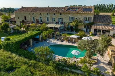 Vue d'une piscine entourée de végétation, avec un jacuzzi, des parasols et un paysage de campagne en arrière-plan.