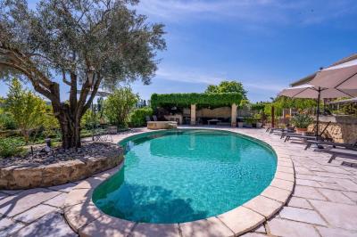 Vue d'une piscine entourée de végétation, avec un jacuzzi, des parasols et un paysage de campagne en arrière-plan.