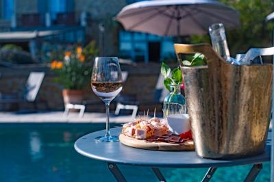 Vue d'une piscine entourée de végétation, avec un jacuzzi, des parasols et un paysage de campagne en arrière-plan.
