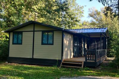 Salle de réception en extérieur décorée pour un événement, avec tables dressées, fleurs et voilages suspendus.