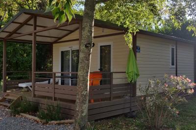 Salle de réception en extérieur décorée pour un événement, avec tables dressées, fleurs et voilages suspendus.