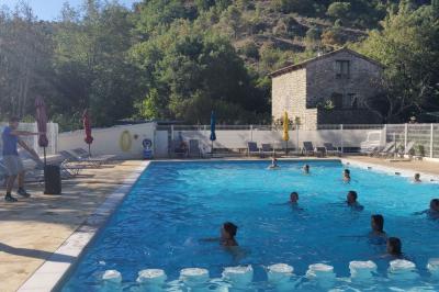 Salle de réception en extérieur décorée pour un événement, avec tables dressées, fleurs et voilages suspendus.