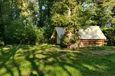 Salle de réception en extérieur décorée pour un événement, avec tables dressées, fleurs et voilages suspendus.