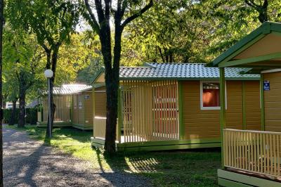 Salle de réception en extérieur décorée pour un événement, avec tables dressées, fleurs et voilages suspendus.