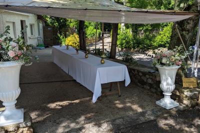 Salle de réception en extérieur décorée pour un événement, avec tables dressées, fleurs et voilages suspendus.