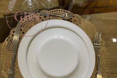 Table dressée avec une assiette blanche, une serviette noire pliée, des couverts, des verres et une carafe d'eau.