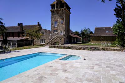 Train en bois pour enfants sur une pelouse, avec une tour en pierre et des arbres en arrière-plan au coucher du soleil.
