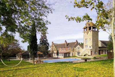 Train en bois pour enfants sur une pelouse, avec une tour en pierre et des arbres en arrière-plan au coucher du soleil.