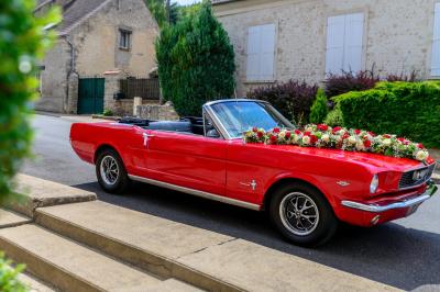 Train en bois pour enfants sur une pelouse, avec une tour en pierre et des arbres en arrière-plan au coucher du soleil.
